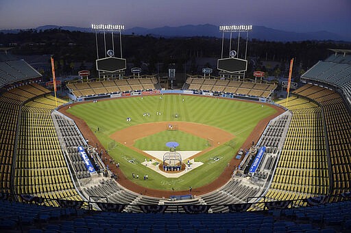 FILE - In Oct. 10, 2018 file photo, Dodger Stadium stands after sunset in Los Angeles. Much of California is shutting down, with theme parks, horse-racing tracks and concert halls locking their doors while some people postpone their weddings as the nation's largest state attempts to dodge the new coronavirus. On Thursday, March 12, 2020, Major League Baseball canceled its opening-day ceremonies for at least two weeks, meaning the 56,000 fans planning to watch the Los Angeles Dodgers play the San Francisco Giants at Dodger Stadium on March 26 will have to find something else to do. (AP Photo/Mark J. Terrill, File)