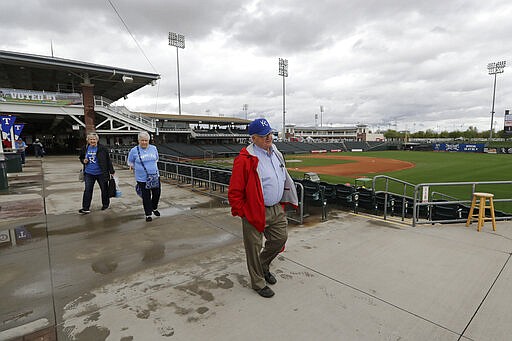 Kansas City Royals fans Ron Bennett, right, Donna Bogue and Kathy Bennett are among the last to head out of the ballpark after the cancelation of a spring training baseball game between the Royals and the Seattle Mariners Thursday, March 12, 2020, in Surprise, Ariz. Major League Baseball is delaying the start of its season by at least two weeks because of the coronavirus outbreak and has suspended the rest of its spring training game schedule. (AP Photo/Elaine Thompson)