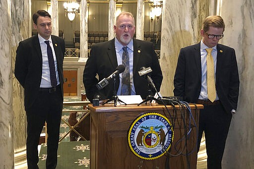 Missouri Senate President Pro Tem Dave Schatz, center, speaks to reporters on Thursday, March 12, 2020, from a gallery overlooking the Senate chamber in Jefferson City, Missouri. Schatz, a Republican, was joined by Democratic Senate Minority Leader John Rizzo, left, and Republican Senate Majority Leader Caleb Rowden, right, in announcing that the Senate will not meet again in full session until at least March 30 because of concerns about the spread of the new coronavirus. For most people, the new coronavirus causes only mild or moderate symptoms, such as fever and cough. For some, especially older adults and people with existing health problems, it can cause more severe illness, including pneumonia. (Photo by David A. Lieb)