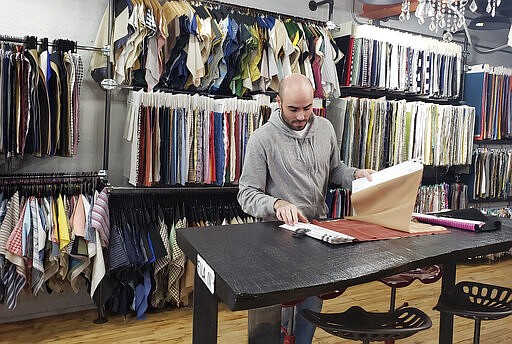 In this March 11, 2020 photo, Giovanni Belotti, looks at materials on a table at FB LP Textiles Inc., in New York City. Belotti is an Italian ex-pat living in New York City. Italians in New York are worried for loved ones in Italy who are living under a nationwide lockdown to stem the spread of the new coronavirus. For most people, the new coronavirus causes only mild or moderate symptoms. For some it can cause more severe illness.(AP Photo/Deepti Hajela)