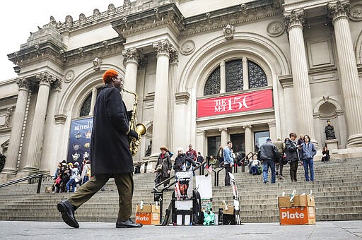 Saxophonist and recording artist Isaiah RIchardson Jr. performs for donations from visitors, arriving and leaving the Metropolitan Museum of Art, Thursday, March 12, 2020, in New York. The Met has announced it will be closing its doors Friday to aid in stopping the spread of the new coronavirus. (AP Photo/Bebeto Matthews)