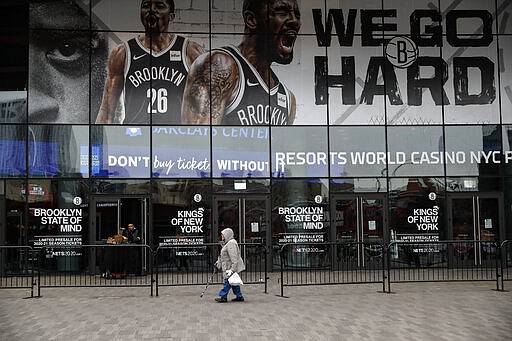 A pedestrian passes an entrance to the Barclays Center in the Brooklyn borough of New York on Thursday, March 12, 2020, after the NCAA's Atlantic 10 Conference Tournament was announced cancelled due to concerns over the COVID-19 coronavirus. (AP Photo/John Minchillo)