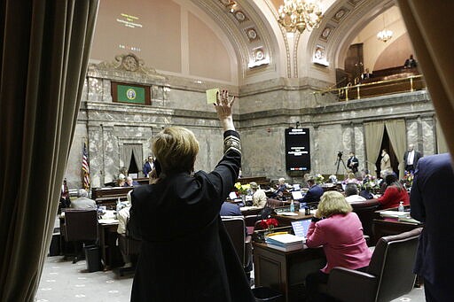 Democratic Sen. Lisa Wellman raises her hand during a vote in the Washington Senate, Thursday, March 12, 2020 in Olympia, Wash. Lawmakers were finishing up their work amid concerns of the state's COVID-19 outbreak. For most people, the new coronavirus causes only mild or moderate symptoms. For some it can cause more severe illness. (AP Photo/Rachel La Corte)