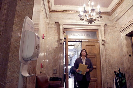 A House page enters the chamber near a sanitizing station, Thursday, March 12, 2020, in Olympia, Wash. Lawmakers were finishing up their work amid concerns of the state's COVID-19 outbreak. For most people, the new coronavirus causes only mild or moderate symptoms. For some it can cause more severe illness. (AP Photo/Rachel La Corte)