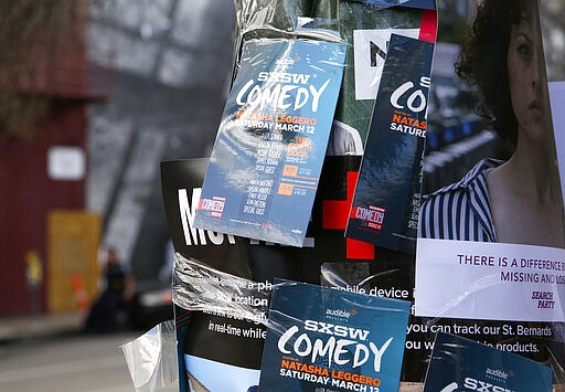 FILE - This March 12, 2016 file photo shows flyers advertising comedy on a light pole on Sixth Street during South By Southwest in Austin, Texas. Austin city officials have canceled the South by Southwest arts and technology festival. Mayor Steve Adler announced a local disaster as a precaution because of the threat of the novel coronavirus, effectively cancelling the annual event that had been scheduled for March 13-22. (Photo by Rich Fury/Invision/AP, File)