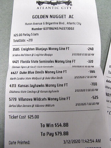 This March 12, 2020, shows a sports betting ticket at the Golden Nugget casino in Atlantic City, N.J. where all five games that were bet on were canceled due to coronavirus precautions. Most professional and college sports events in the U.S. have been suspended or delayed, leaving little to bet on. For most people, the new coronavirus causes only mild or moderate symptoms. For some it can cause more severe illness.(AP Photo/Wayne Parry)