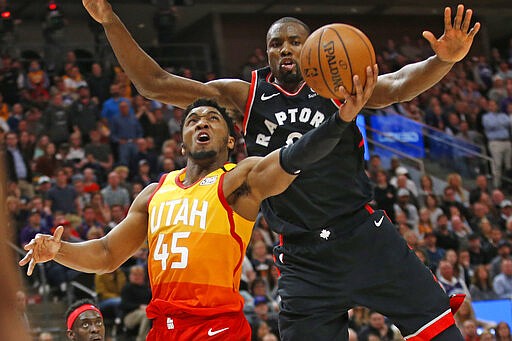 Toronto Raptors center Serge Ibaka, rear, defends against Utah Jazz guard Donovan Mitchell (45) who goes to the basket in the second half during an NBA basketball game Monday, March 9, 2020, in Salt Lake City. (AP Photo/Rick Bowmer)