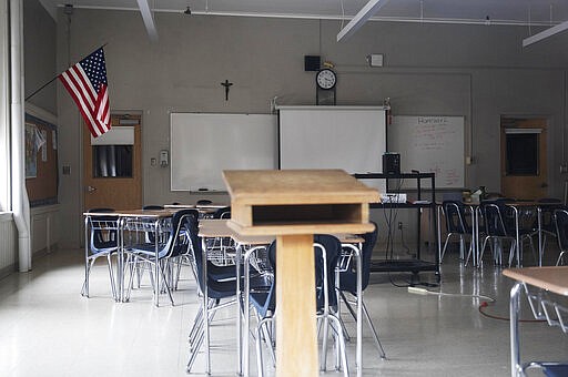 FILE - This March 6, 2020, file photo, shows a classroom vacant through a window at Saint Raphael Academy in Pawtucket, R.I., as the school remains closed following a confirmed case of the coronavirus. (AP Photo/David Goldman, File)