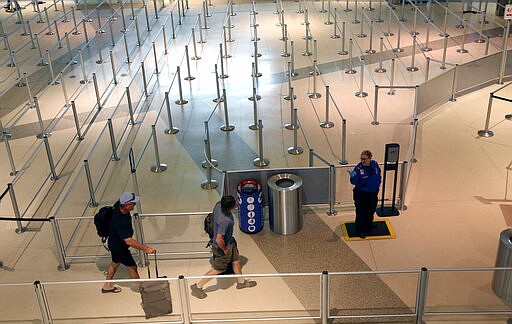 A TSA agent speaks to travelers passing through an empty security queue at Love Field airport in Dallas, Thursday, March 12, 2020, amid concerns of the coronavirus pandemic. (AP Photo/LM Otero)