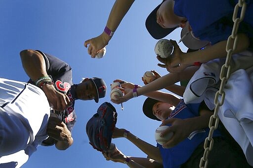 Cleveland Indians' Francisco Lindor, left, signs autographs for fans, signing gloves, baseballs, hats and uniforms prior to the team's spring training baseball game against the Chicago Cubs on Saturday, March 7, 2020, in Goodyear, Ariz. Lindor and many Indians players signed autographs for fans Saturday, even as the MLB set new policies in place as a precaution due to the coronavirus. (AP Photo/Ross D. Franklin)