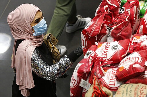 A woman wears a mask and gloves, as she checks products at a supermarket as people begin to stock up on provisions, in Beirut, Lebanon, Wednesday, March 11, 2020.  Health Ministry officials say there are more confirmed cases of the coronavirus in Lebanon.  The vast majority of people recover from this virus. (AP Photo/Hussein Malla)