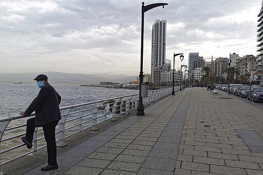 A man wears a mask to help protect himself from the new coronavirus looks towards at Beirut's seaside corniche, or waterfront promenade, along the Mediterranean Sea, is almost empty of residents and tourists in Beirut, Lebanon, Thursday, March 12, 2020. For most people, the new coronavirus causes only mild or moderate symptoms, such as fever and cough. For some, especially older adults and people with existing health problems, it can cause more severe illness, including pneumonia. (AP Photo/Hassan Ammar)