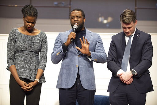 In this Saturday, Feb. 22, 2020 photo, incumbent Cook County State's Attorney Kim Foxx, left,  prays with Senior Pastor, Rev. Dr. Charles E. Dates, center, and candidate Bill Conway, right, at the 2020 Primary Candidates' Forum at the Progressive Baptist Church in Chicago. The Chicago area's top prosecutor is trying to convince voters of her criminal justice reform record as she faces continued questions about her handling of actor Jussie Smollett's case. (Colin Boyle/Chicago Sun-Times via AP)
