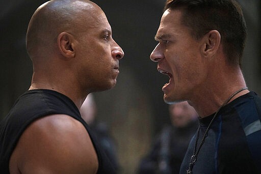 This image released by Universal Pictures shows Vin Diesel, left, and John Cena in a scene from &quot;F9.&quot; Universal Pictures announced that the &#147;Fast and Furious&#148; movie titled &#147;F9&#148; would not open May 22 as planned but in April next year due to the coronavirus. For most people, the new coronavirus causes only mild or moderate symptoms. For some it can cause more severe illness. (Giles Keyte/Universal Pictures via AP)