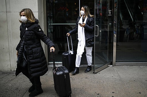 Shoppers wear face masks as they walk in New York's Herald Square on Thursday, March 12, 2020. Mayor Bill de Blasio said Thursday he will announce new restrictions on gatherings to halt the spread of the new coronavirus in the coming days, but he hopes to avoid closing all public events such as Broadway shows. (AP Photo/John Minchillo)