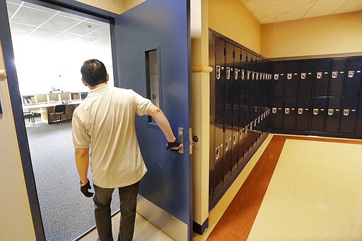 FILE - In this Feb. 27, 2020 file photo, a school janitor opens the door to a staff room inside Bothell High School which was closed for the day, in Bothell, Wash., after a staffer's family member was placed in quarantine for showing symptoms of possibly contracting the new coronavirus. Many parents are now deciding how to talk to their children about the virus. Some said they are checking in daily, while others worry talking about it could make their kids more anxious or fearful. (AP Photo/Elaine Thompson, File)