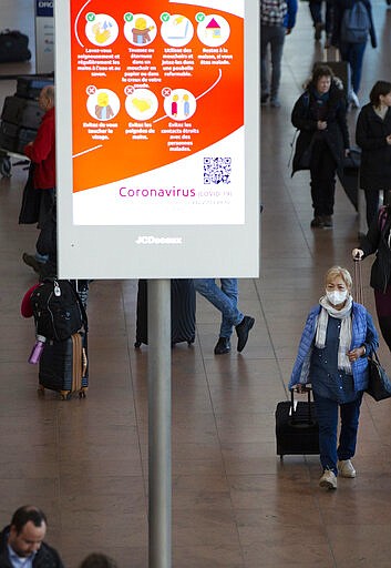 A woman wears a protective mask as she walks in the main terminal of Brussels International Airport in Brussels, Thursday, March 12, 2020. The European Union has slammed the new anti-virus travel ban announced by U.S. President Donald Trump on Wednesday. For most people, the new coronavirus causes only mild or moderate symptoms, such as fever and cough. For some, especially older adults and people with existing health problems, it can cause more severe illness, including pneumonia.(AP Photo/Virginia Mayo)