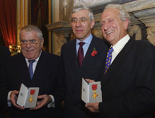 FILE - In this Thursday, Oct. 31, 2002 file photo, Albert, left, and Michel Roux, right, receive their Order of the British Empire honorary awards from the British Foreign Secretary Jack Straw during a ceremony at the Foreign Office in London. Michel Roux, the French-born chef who had a profound influence on Britain's fine dining habits, has died on Thursday, March 12, 2020. He was 78. (AP Photo/Alastair Grant, file)