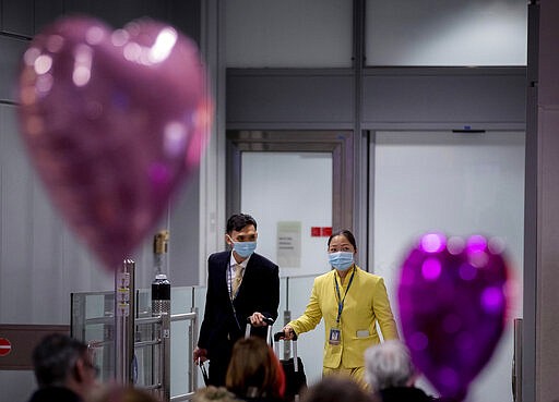 Flight attendants of an Asian airline wear face masks as they arrive at the airport in Frankfurt, Germany, Wednesday, March 11, 2020. Due to the spread of the Coronavirus a large number of flights have to be cancelled. For most people, the new coronavirus causes only mild or moderate symptoms, such as fever and cough. For some, especially older adults and people with existing health problems, it can cause more severe illness, including pneumonia. (AP Photo/Michael Probst)