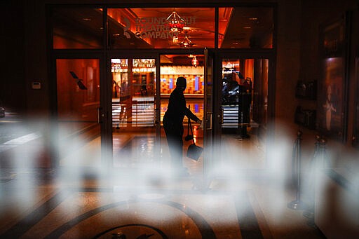 A custodian cleans the lobby of the Roundabout Theatre Company in Times Square, Thursday, March 12, 2020, in New York. New York City Mayor Bill de Blasio said Thursday he will announce new restrictions on gatherings to halt the spread of the new coronavirus in the coming days. For most people, the new coronavirus causes only mild or moderate symptoms. For some it can cause more severe illness. (AP Photo/John Minchillo)