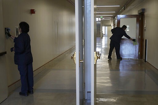 Janitors clean in a hallway in Wheeler Hall on the University of California campus in Berkeley, Calif., Wednesday, March 11, 2020. UC Berkeley has suspended in-person classes due to coronavirus concerns. (AP Photo/Jeff Chiu)