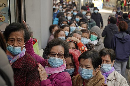 In this Thursday, Jan. 30, 2020, file photo, people line up to buy face masks at a cosmetics shop in Hong Kong. Last year, face masks were the signature of Hong Kong&#146;s protesters, who wore them to protect against tear gas and conceal their identities from authorities. These same masks are now ubiquitous around the world -- worn by people from China and Iran, to Italy and America, seeking to protect against the coronavirus.  The vast majority of people recover from the new virus. (AP Photo/Kin Cheung, File)