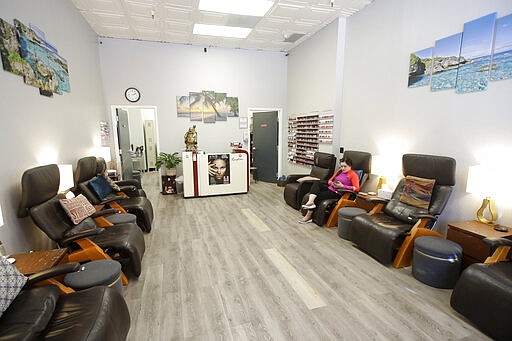 Pampered Hands Salon worker Nguyen Ho sits in an empty store in San Francisco, Thursday, March 12, 2020. For most people, the new coronavirus causes only mild or moderate symptoms. For some it can cause more severe illness. (AP Photo/Jeff Chiu)