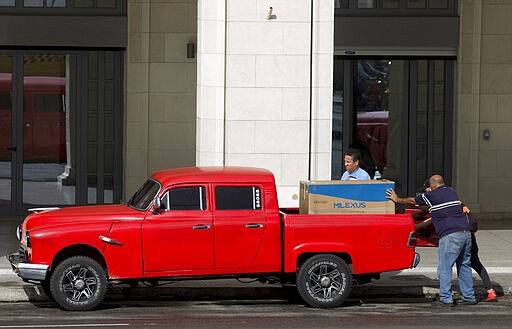 Men load up a newly bought refrigerator onto a truck in Havana, Cuba, Monday, March 9, 2020. In recent months, Cuban authorities have started to promote websites that allow people to pay in U.S. dollars through a credit card for items including flowers, meat, mattresses and air conditioners. Items like refreigerators are only available to be bought in dollars. (AP Photo/Ismael Francisco)