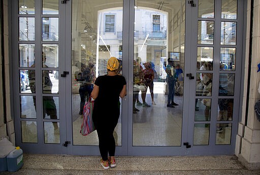 A woman watches what new products are for sale at the 4 Caminos market in Havana, Cuba, Wednesday, March 11, 2020. One year after the Cuban government authorized mobile data services, thousands of Cubans are now using social media messaging apps to find foodstuffs and supplies that have become scarce since the administration of U.S. President Donald Trump hardened its economic sanctions against the island nation. (AP Photo/Ismael Francisco)