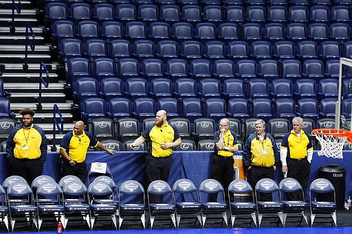 Security guards stand behind a team bench area at Bridgestone Arena after the NCAA college basketball games at the Southeastern Conference men's tournament were cancelled, Thursday, March 12, 2020, in Nashville, Tenn. The tournament was cancelled due to coronavirus concerns.  (AP Photo/Mark Humphrey)