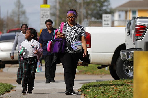 Danielle Tucker walks with her daughter Mariah Tucker, 5, after school was adjourned at the Dr.Martin Luther King, Jr. Elementary School for Science and Technology in New Orleans, Friday, March 13, 2020. Louisiana Gov. John Bel Edwards on Friday closed K-12 public schools across the state for roughly a month and banned gatherings of more than 250 people in an effort to slow the spread of the coronavirus. For most people, the new coronavirus causes only mild or moderate symptoms. For some it can cause more severe illness. (AP Photo/Gerald Herbert)