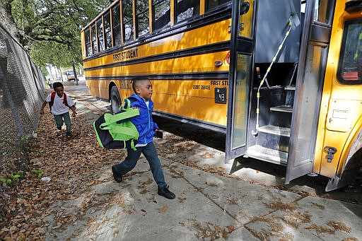 Childern board a school bus after school was adjourned at the Dr. Martin Luther King, Jr. Elementary School for Science and Technology in New Orleans, Friday, March 13, 2020. Louisiana Gov. John Bel Edwards on Friday closed K-12 public schools across the state for roughly a month and banned gatherings of more than 250 people in an effort to slow the spread of the coronavirus. He said he also planned to postpone the presidential primary until June. (AP Photo/Gerald Herbert)