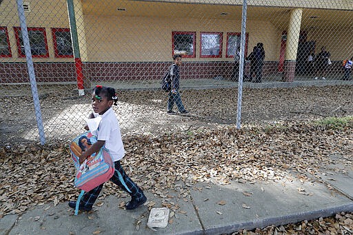 A child walks to board a school bus after school was adjourned at the Dr. Martin Luther King, Jr. Elementary School for Science and Technology in New Orleans, Friday, March 13, 2020. Louisiana Gov. John Bel Edwards on Friday closed K-12 public schools across the state for roughly a month and banned gatherings of more than 250 people in an effort to slow the spread of the coronavirus. For most people, the new coronavirus causes only mild or moderate symptoms. For some it can cause more severe illness. (AP Photo/Gerald Herbert)