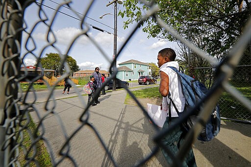 Parents wait as children leave after school was adjourned for the day at the Dr. Martin Luther King, Jr. Elementary School for Science and Technology in New Orleans, Friday, March 13, 2020. Louisiana Gov. John Bel Edwards on Friday closed K-12 public schools across the state for roughly a month and banned gatherings of more than 250 people in an effort to slow the spread of the coronavirus. For most people, the new coronavirus causes only mild or moderate symptoms. For some it can cause more severe illness. (AP Photo/Gerald Herbert)