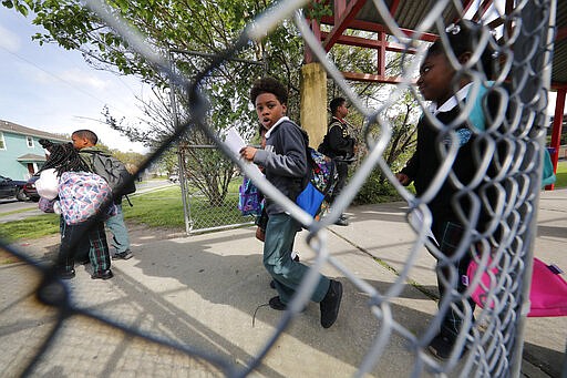 Children leave after school was adjourned at the Dr. Martin Luther King, Jr. Elementary School for Science and Technology in New Orleans, Friday, March 13, 2020. Louisiana Gov. John Bel Edwards on Friday closed K-12 public schools across the state for roughly a month and banned gatherings of more than 250 people in an effort to slow the spread of the coronavirus. For most people, the new coronavirus causes only mild or moderate symptoms. For some it can cause more severe illness. (AP Photo/Gerald Herbert)