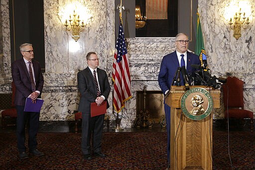 Washington Gov. Jay Inslee, right, talks to the media about the decision to close schools in three counties in response to COVID-19, on Thursday, March 12, 2020, in Olympia, Wash. At left are state Health Secretary John Wiesman, and Superintendent of Public Instruction Chris Reykdal. All public and private K-12 schools in King, Pierce and Snohomish counties will be closed for six weeks, and Inslee said there could be closures in more counties soon. (AP Photo/Rachel La Corte)
