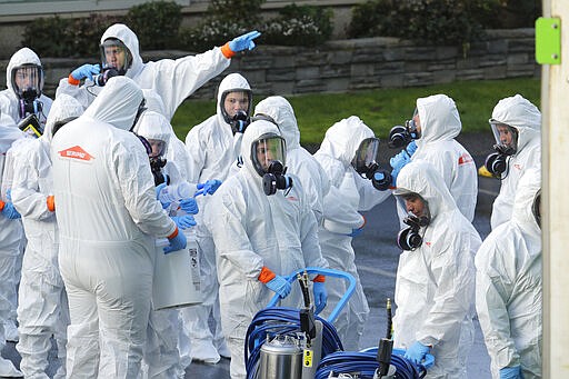 Workers from a Servpro disaster recovery team wearing protective suits and respirators enter the Life Care Center in Kirkland, Wash., to begin cleaning and disinfecting the facility, Wednesday, March 11, 2020, near Seattle. The nursing home is at the center of the coronavirus outbreak in Washington state. For most people, the virus causes only mild or moderate symptoms. For some it can cause more severe illness, especially in older adults and people with existing health problems. (AP Photo/Ted S. Warren)