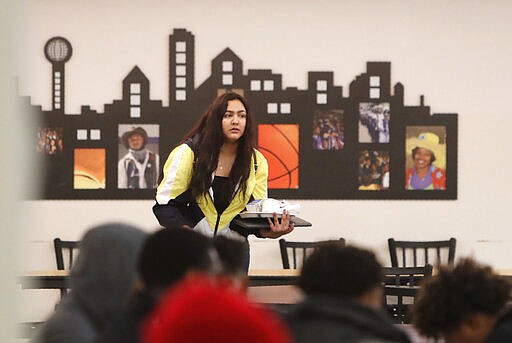 A student carries their lunch tray of food in the cafeteria at Lincoln High School in Dallas, Friday, March 13, 2020. During the coming extended spring break school closures, this cafeteria and a few others in the Dallas Independent School District will be providing lunches to students despite the closure of the school. (AP Photo/LM Otero)