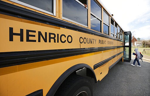 A student gets on a bus to go home at Glen Lea Elementary School, Friday, March 13, 2020 in Richmond, Va. Virginia Gov. Ralph Northam on Friday ordered all schools in Virginia to close for at least two weeks as the coronavirus spreads, a move that follows similar orders in several other states. (Joe Mahoney/Richmond Times-Dispatch via AP)