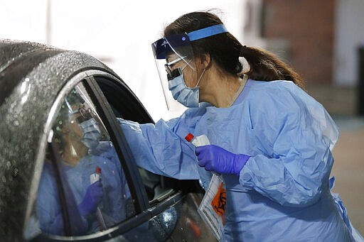 A nurse at a drive-up coronavirus testing station set up by the University of Washington Medical Center uses a swab to take a sample from the nose of a person in a car Friday, March 13, 2020, in Seattle. UW Medicine is conducting drive-thru testing in a hospital parking garage and has screened hundreds of staff members, faculty and trainees for COVID-19. U.S. hospitals are setting up triage tents, calling doctors out of retirement, guarding their supplies of face masks and making plans to cancel elective surgery as they brace for an expected onslaught of coronavirus patients. (AP Photo/Ted S. Warren)