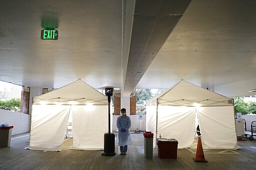 A nurse at a drive up COVID-19 coronavirus testing station set up by the University of Washington Medical Center wears a face shield, mask, and other protective gear as she waits by tents, Friday, March 13, 2020, in Seattle. UW Medicine is conducting drive-thru testing in a hospital parking garage and has screened hundreds of staff members, faculty and trainees for the COVID-19 coronavirus. U.S. hospitals are setting up triage tents, calling doctors out of retirement, guarding their supplies of face masks and making plans to cancel elective surgery as they brace for an expected onslaught of coronavirus patients. (AP Photo/Ted S. Warren)