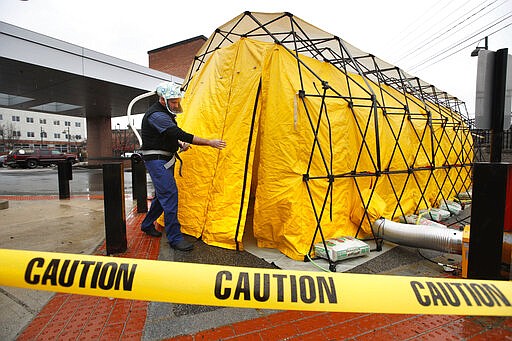 Steve Moody, director of nursing at Central Maine Medical Center, enters a tent outside the emergency entrance to the hospital to test patients who have symptoms of the coronavirus, Friday, March 13, 2020, in Lewiston, Maine. U.S. hospitals are setting up circus-like triage tents, calling doctors out of retirement, guarding their supplies of face masks and making plans to cancel elective surgery as they brace for an expected onslaught of coronavirus patients. (AP Photo/Robert F. Bukaty)