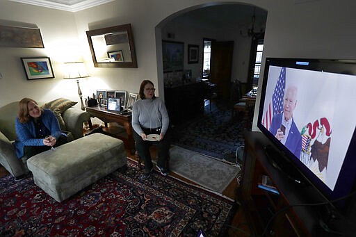 Lally Doerrer, right, and Katharine Hildebrand watch Joe Biden during his Illinois virtual town hall, in Doerrer's living room Friday, March 13, 2020, in Chicago. (AP Photo/Charles Rex Arbogast)