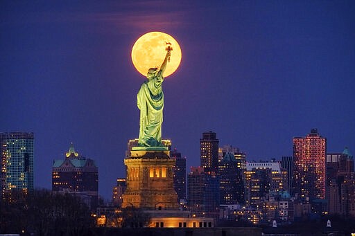 The rising full moon crosses behind the Statue of Liberty, Monday evening, March 9, 2020, in New York City. (AP Photo/J. David Ake)