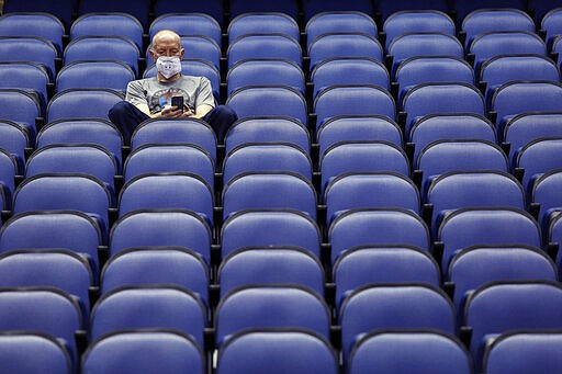 Mike Lemcke, from Richmond, Va., sits in an empty Greensboro Coliseum after the NCAA college basketball games were canceled at the Atlantic Coast Conference tournament in Greensboro, N.C., Thursday, March 12, 2020. (AP Photo/Ben McKeown)