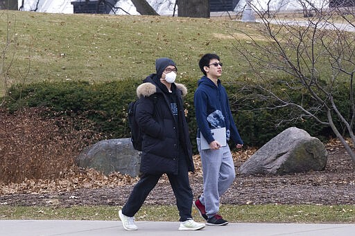 A masked pedestrian walks near Camp Randall Stadium Thursday, March 12, 2020 on the campus of UW-Madison in Madison, Wis. The university is one of multiple Wisconsin universities on Wednesday took dramatic steps to ward off or curb the spread of the COVID-19 outbreak, everything from moving courses online to canceling university-sponsored travel and events to extending spring break. (Mark Hoffman/Milwaukee Journal-Sentinel via AP)