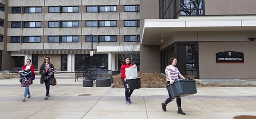 Calli Fiez, right, and her mother, Kim, carry her belongings to their car while moving out of Witte Residence Hall Thursday, March 12, 2020 on the campus of UW-Madison in Madison, Wis. The university is one of multiple Wisconsin universities on Wednesday took dramatic steps to ward off or curb the spread of the COVID-19 outbreak, everything from moving courses online to canceling university-sponsored travel and events to extending spring break. Fiez is a freshman from Monroe, Wis. (Mark Hoffman/Milwaukee Journal-Sentinel via AP)