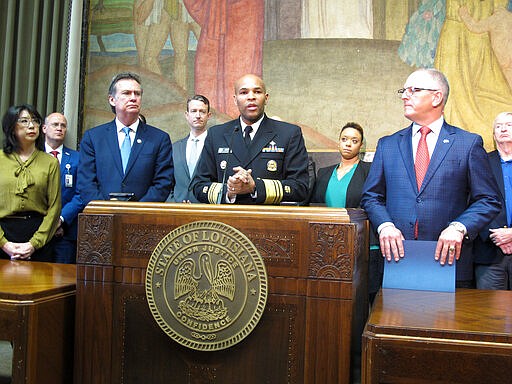 U.S. Surgeon General Jerome Adams, center, speaks about the new coronavirus, while Louisiana Gov. John Bel Edwards, right, listens on Thursday, March 12, 2020, in Baton Rouge, La. The number of cases of the COVID-19 disease caused by the virus are on the rise in Louisiana. (AP Photo/Melinda Deslatte)