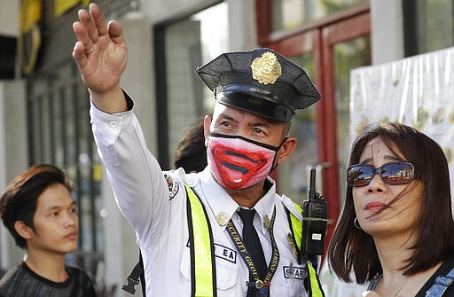 A security guard wearing a protective mask assists a woman in Manila, Philippines Friday, March 13, 2020. Many people adjusted their travel plans ahead of a government suspension of domestic travel to and from metropolitan Manila. Philippine President Rodrigo Duterte also authorized sweeping quarantines in the crowded capital to fight the new coronavirus. For most people, the new coronavirus causes only mild or moderate symptoms. For some it can cause more severe illness. (AP Photo/Aaron Favila)