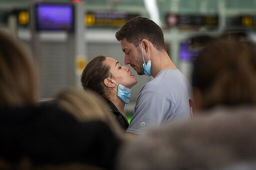 A couple kiss,  at the Barcelona airport, Spain, Thursday, March 12, 2020. President Donald Trump, who had downplayed the coronavirus for weeks, suddenly struck a different tone, announcing strict rules on restricting travel from much of Europe to begin this weekend. For most people, the new coronavirus causes only mild or moderate symptoms, such as fever and cough. For some, especially older adults and people with existing health problems, it can cause more severe illness, including pneumonia. (AP Photo/Emilio Morenatti)